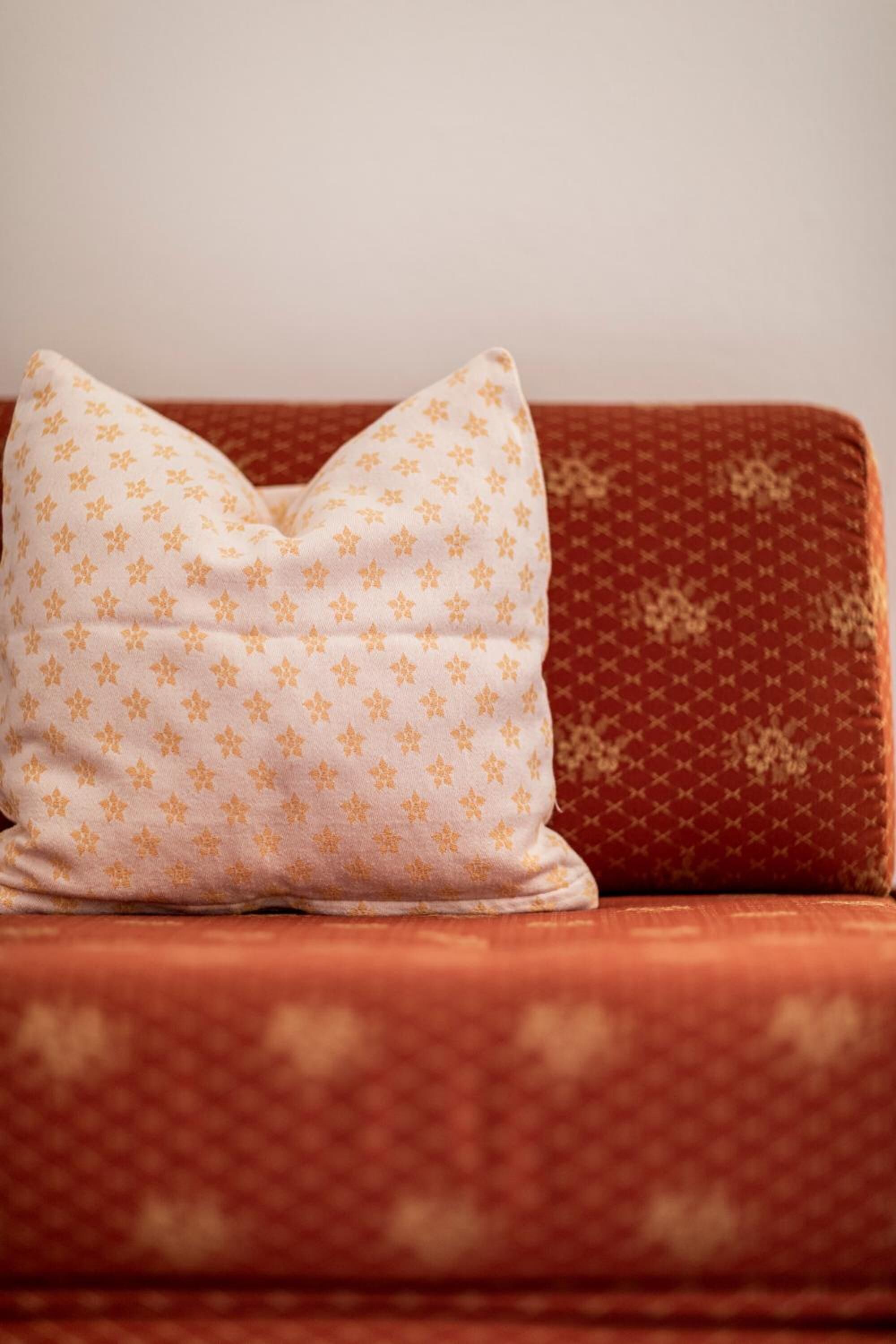 Ein rotes Sofa mit einem gemusterten und einem schlichten Kissen.
