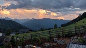 A mountainous landscape with a wooden fence, a stone pathway, and a small building. - Hotel Rommisa (Perca)