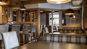 Un restaurante con mobiliario de madera, iluminación colgante y vistas amplias a través de grandes ventanales.