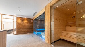 A modern spa area with wooden walls, a glass-enclosed sauna, and a wooden bench. - Hotel Rommisa (Perca)