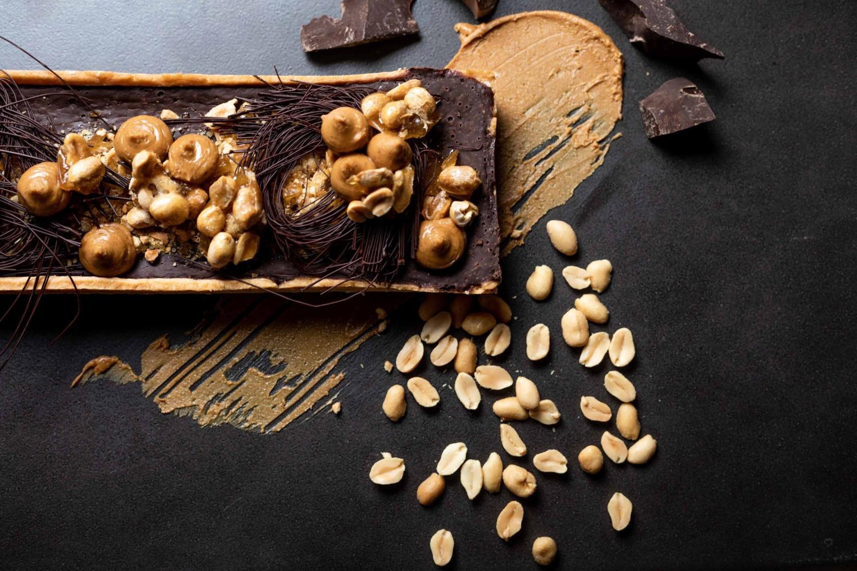 A tray with peanuts and hazelnuts on a dark surface.