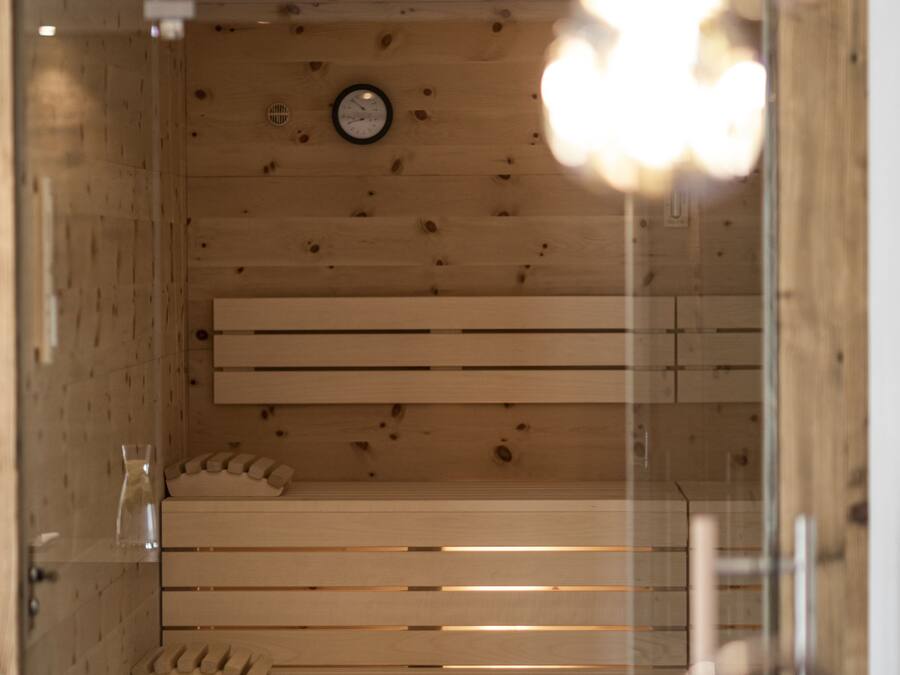 Un interior de madera con un banco, un reloj y una puerta de cristal.