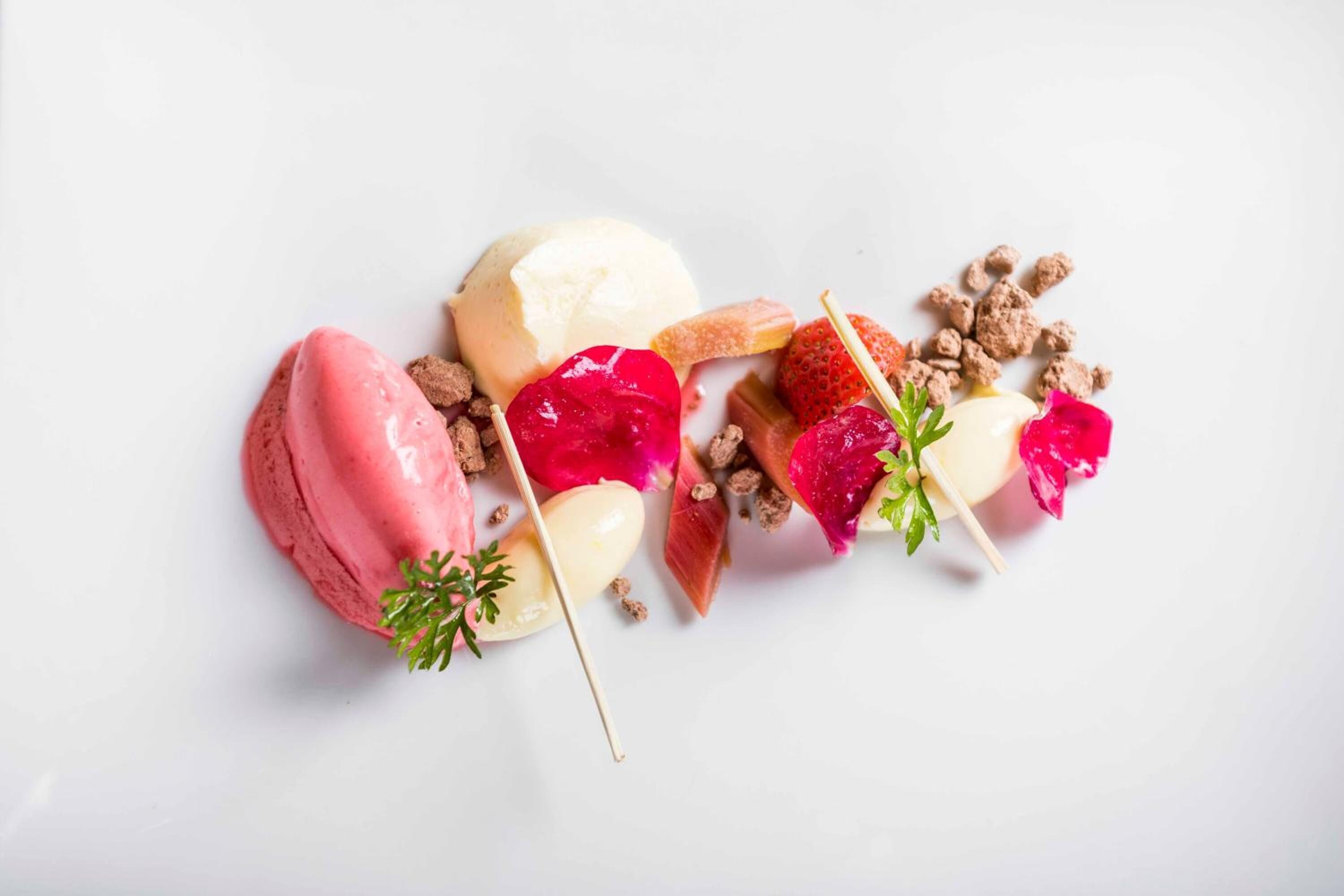 Un plato de postre con helado, fruta y nueces.