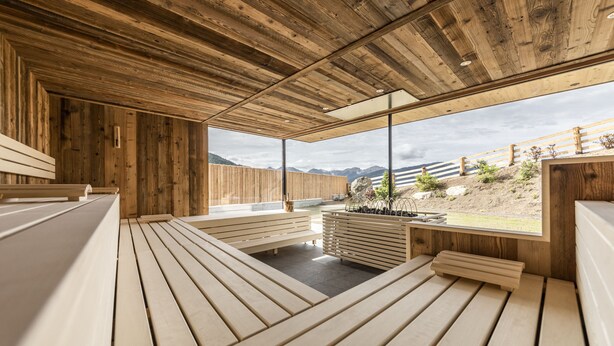 A wooden interior with benches and a view of mountains. - Hotel Rommisa (Perca)