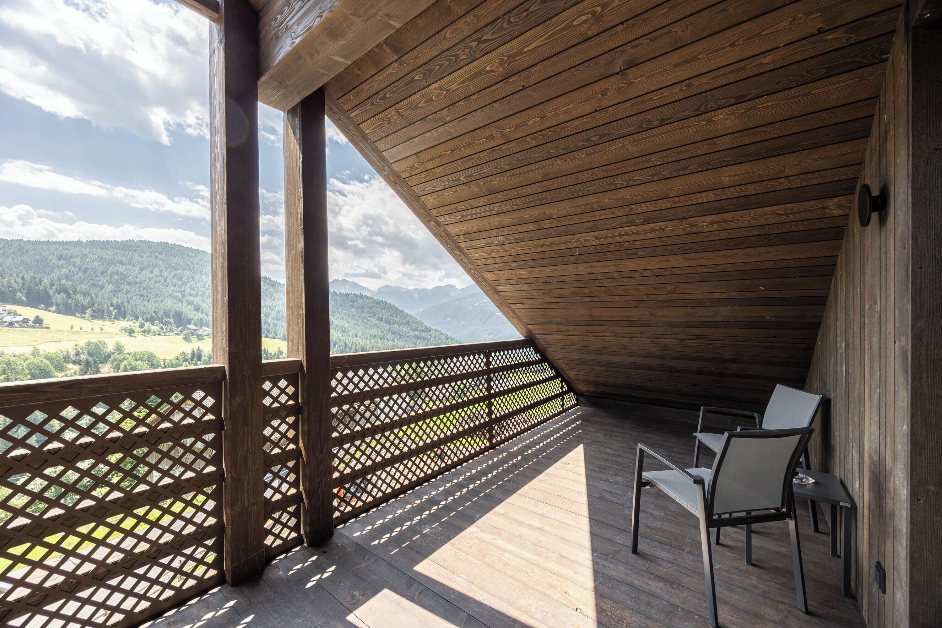 Una terraza de madera con vista a un paisaje montañoso.