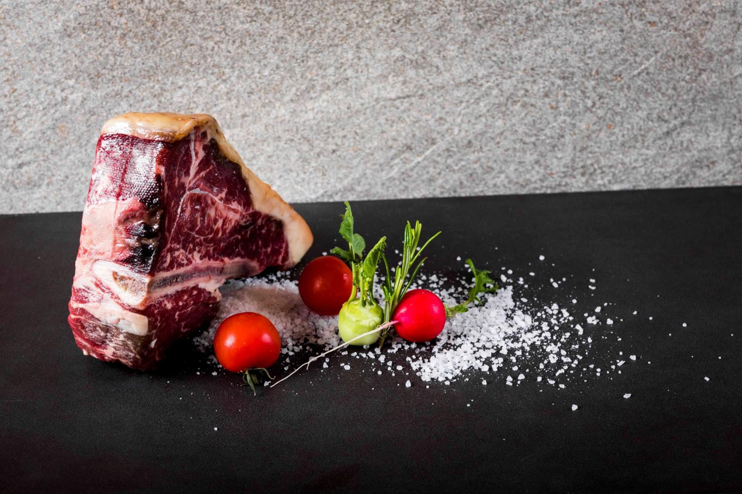 Una bistecca con ravanelli e sale su una superficie scura.