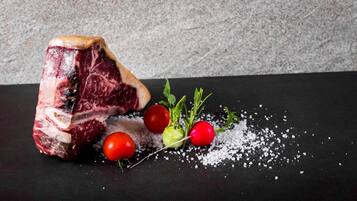 Un bistec con rábanos y sal sobre una superficie oscura.