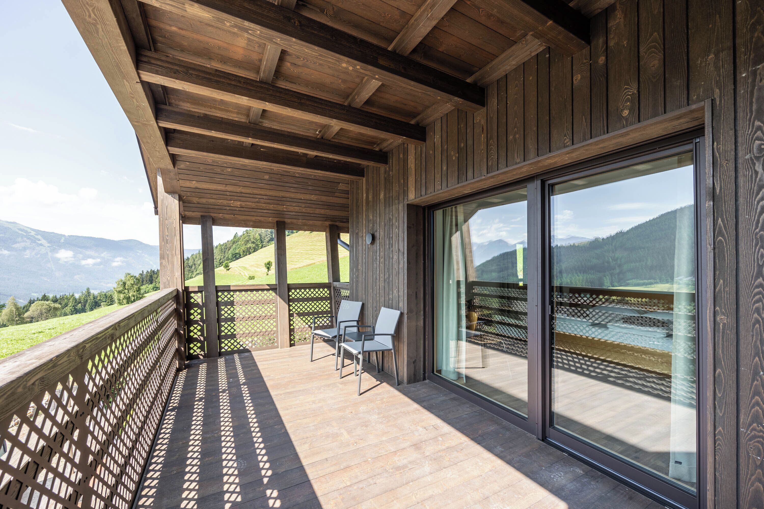 Un balcon en bois offrant une vue sur un paysage montagneux.