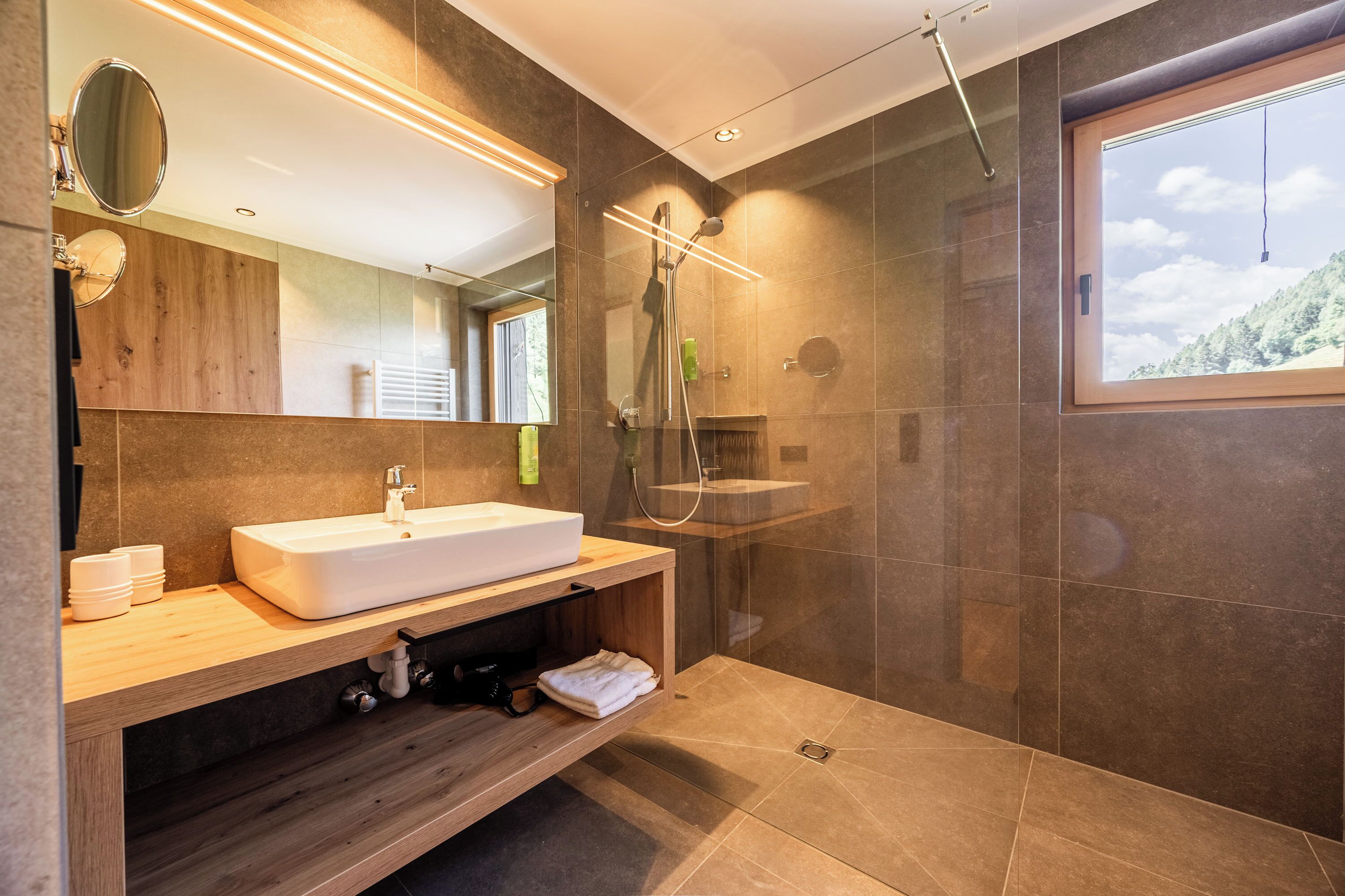Un baño moderno con un lavamanos grande, espejo y ducha.