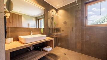 Un baño moderno con un lavamanos grande, espejo y ducha.