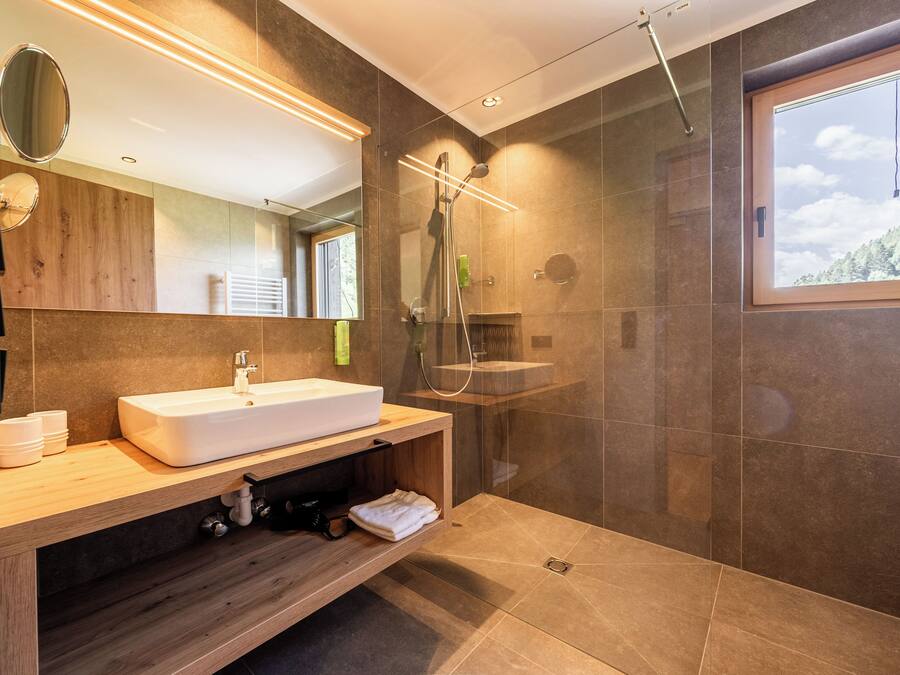Un baño moderno con un lavamanos grande, espejo y ducha.