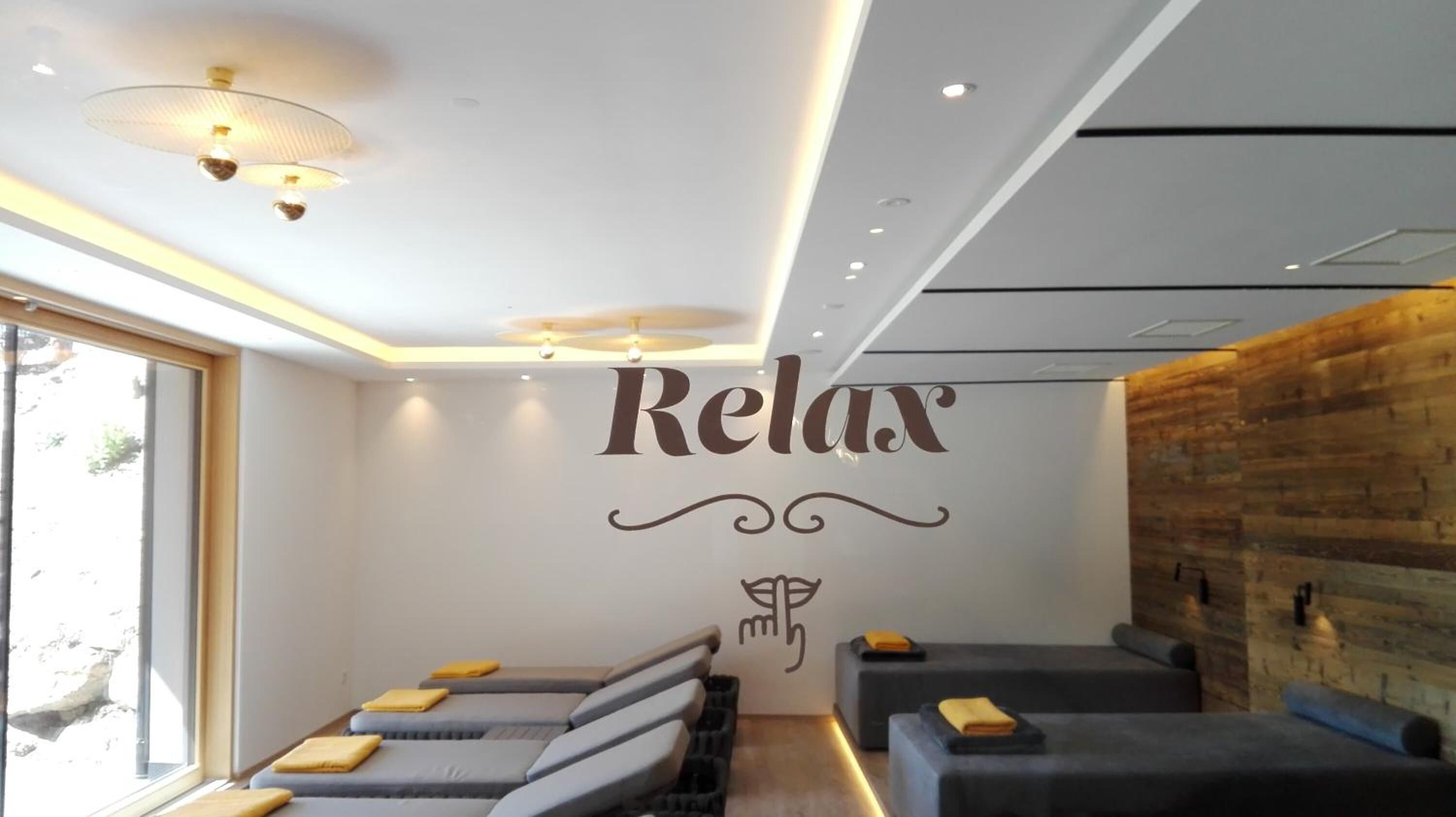 A spa room with a 'Relax' sign, massage tables, and a wooden wall.
