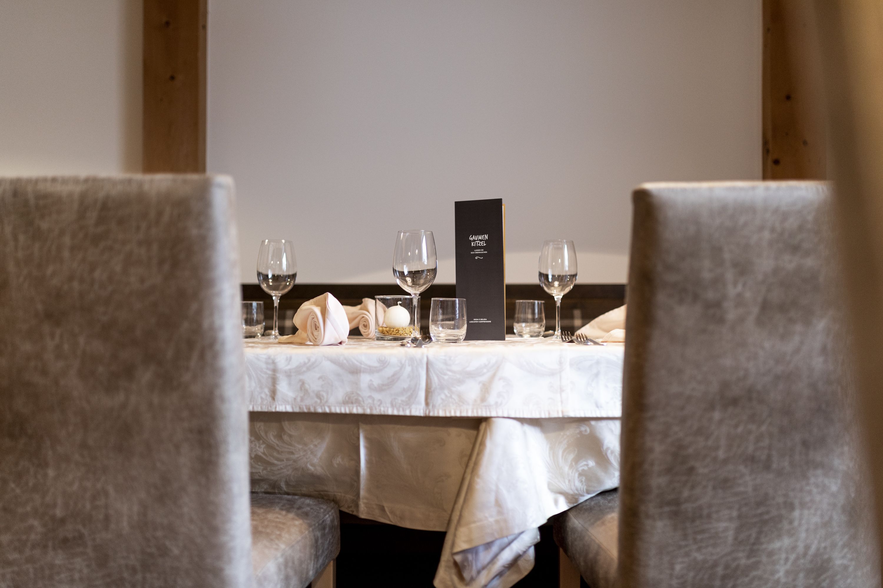 A dining table set with wine glasses, a menu, and a folded napkin.