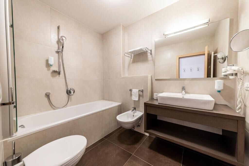 A modern bathroom with a bathtub, a shower, a bidet, a toilet, and a vanity with a mirror.
