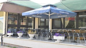 Un restaurante con terraza al aire libre, cubierto por sombrillas y plantas en macetas.