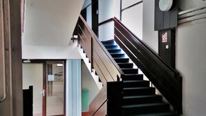 Una escalera que sube a un piso superior, con barandilla y una puerta al final.