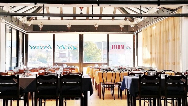 Un restaurante con varias mesas y sillas, amplios ventanales y vistas al exterior.