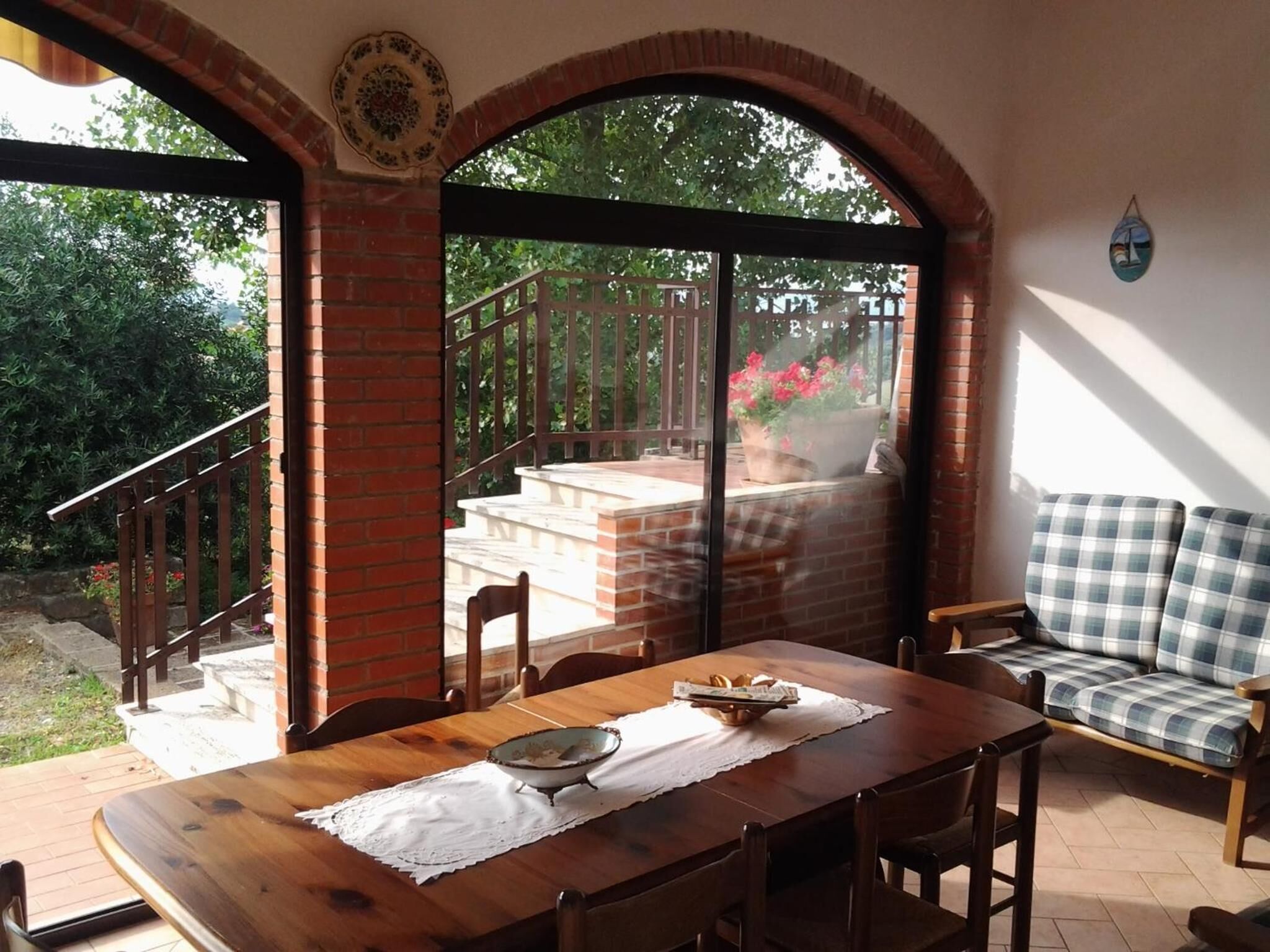 Comedor con mesa de madera, sillas y vista a un jardín a través de un ventanal.