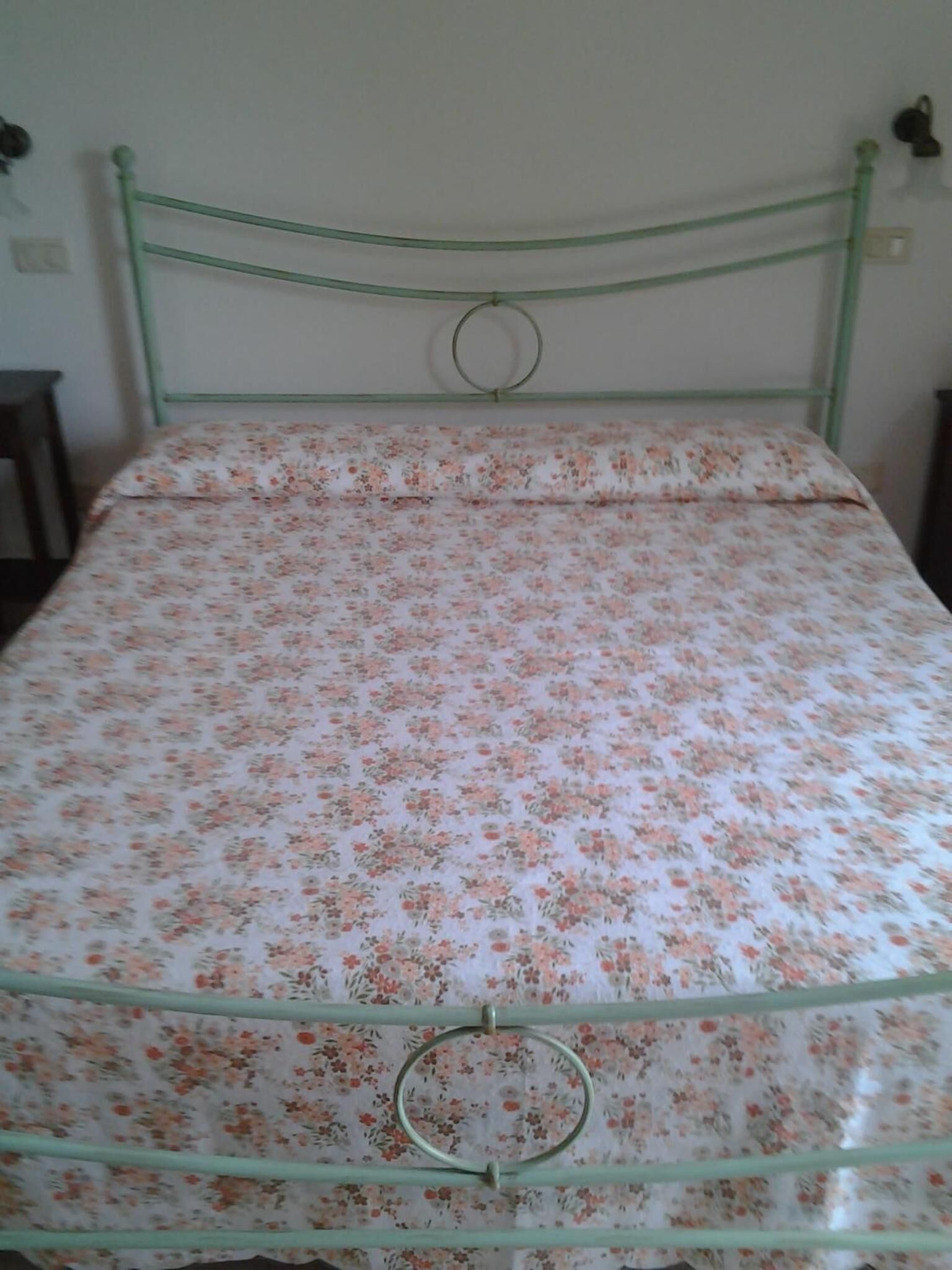 A single bed with a floral bedspread and a metal frame.