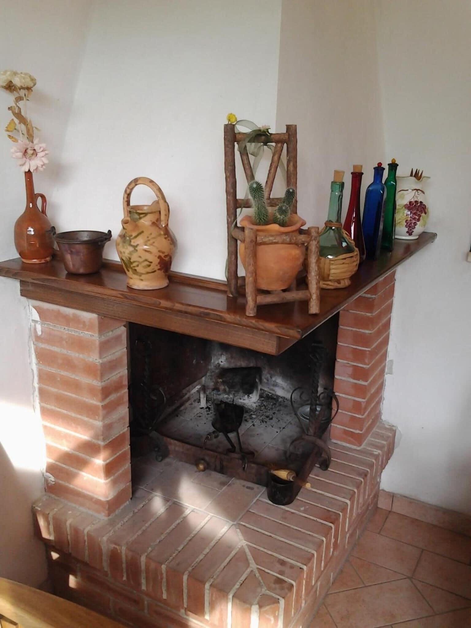A brick fireplace with a shelf above it holding various decorative items.