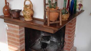 A brick fireplace with a shelf above it holding various decorative items.