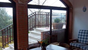 A dining area with a table set for two, a vase with flowers, and a view of a balcony with steps and a railing. - Agriturismo Norianino (Manciano)
