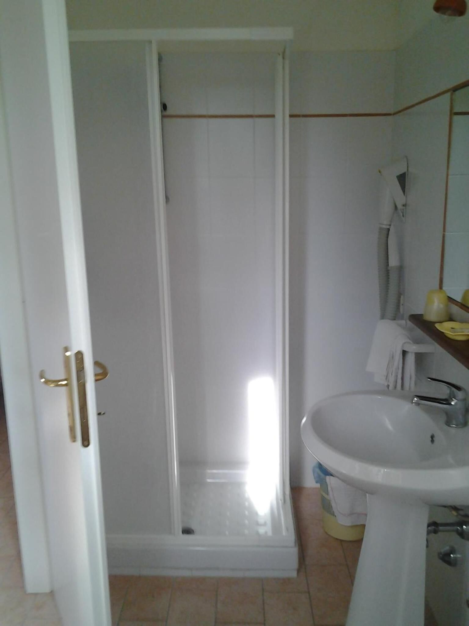 Kylpyhuone, jossa on suihku, pesuallas ja peili.