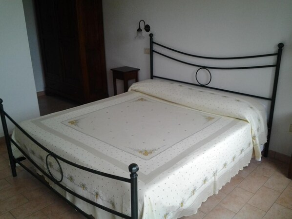 A single bed with a metal frame and a white bedspread with floral patterns.