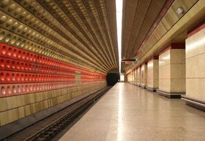 A subway station with a long platform, tiled walls, and a train track. - Golden Angel Apartment (Prague)