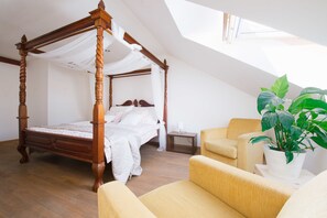 A four-poster canopy bed with a nightstand and a potted plant in a modern bedroom with a sloped ceiling and skylight. - Golden Angel Apartment (Prague)