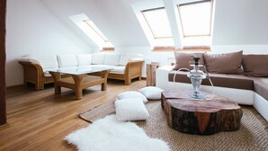 A modern loft apartment with a high ceiling, wooden flooring, a white sofa, a wicker coffee table, and a wooden coffee table with a hookah. - Golden Angel Apartment (Prague)