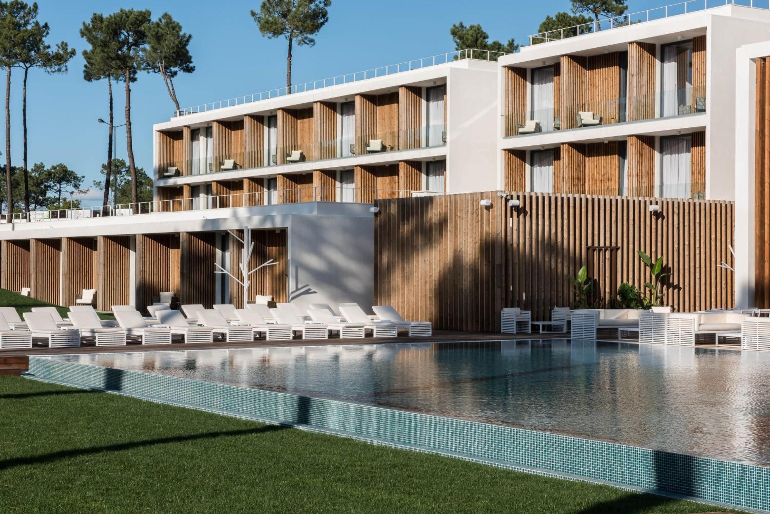 A modern hotel with a pool area, multiple balconies, and a wooden facade.