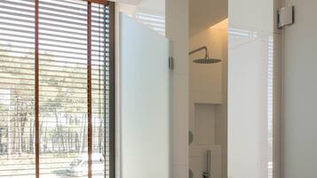 A modern bathroom with a freestanding bathtub, a glass-enclosed shower, and a window with blinds.