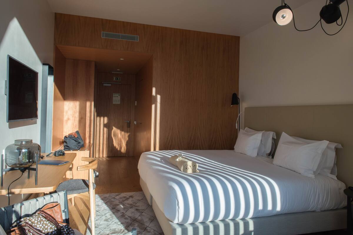 Ein Hotelzimmer mit Bett, Schreibtisch, Stuhl und Kleiderschrank.