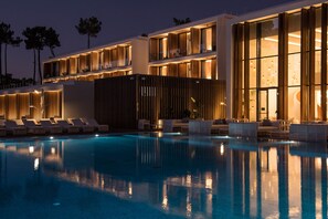 Ein modernes Hotel mit Schwimmbad, Loungebereichen und großen Fenstern.