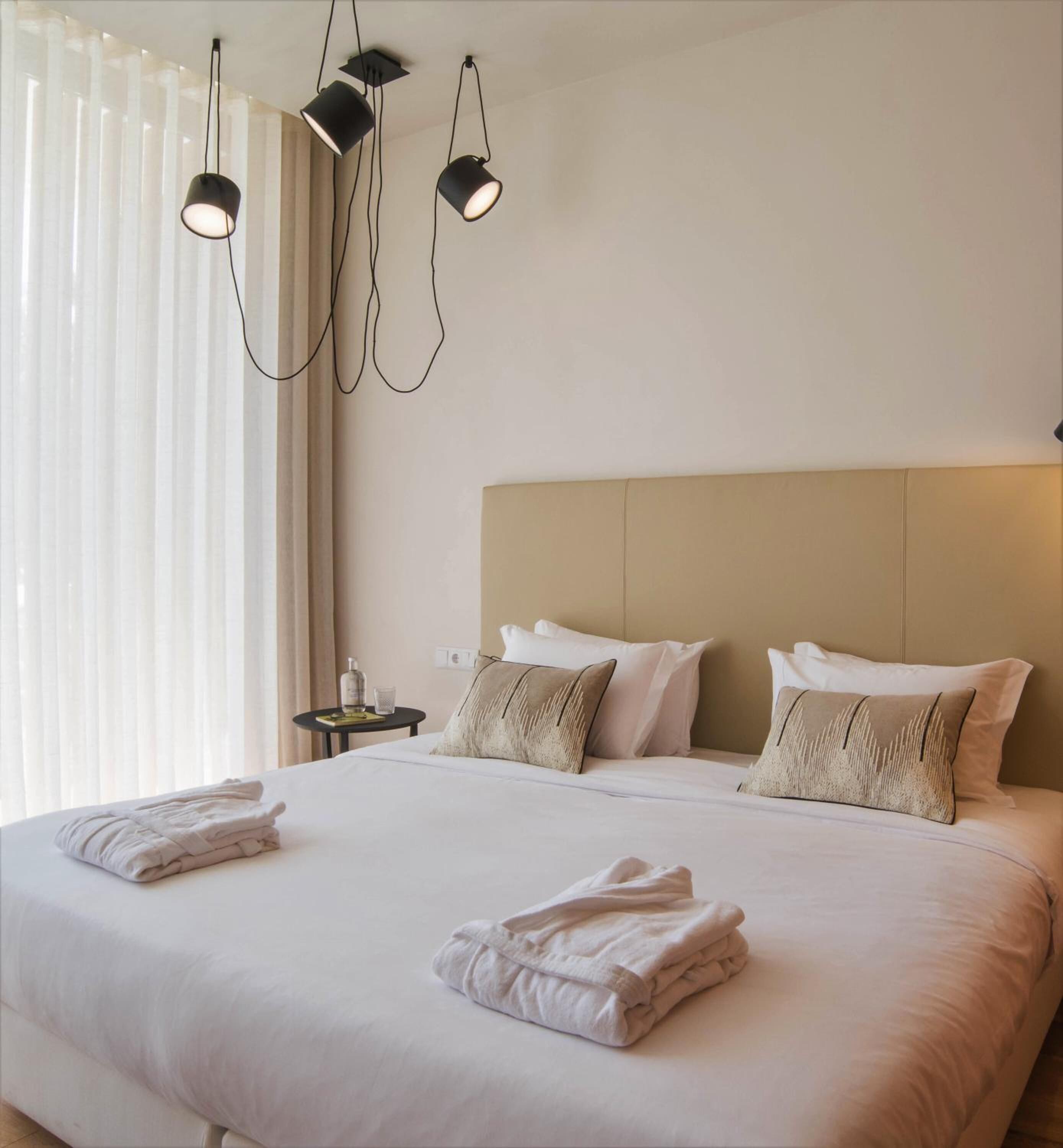 Een hotelkamer met een groot bed, twee nachtkastjes en drie hanglampen.