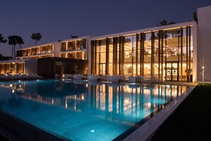 Ein modernes Hotel mit Schwimmbad, mehreren Balkonen und gut beleuchteten Innenräumen.