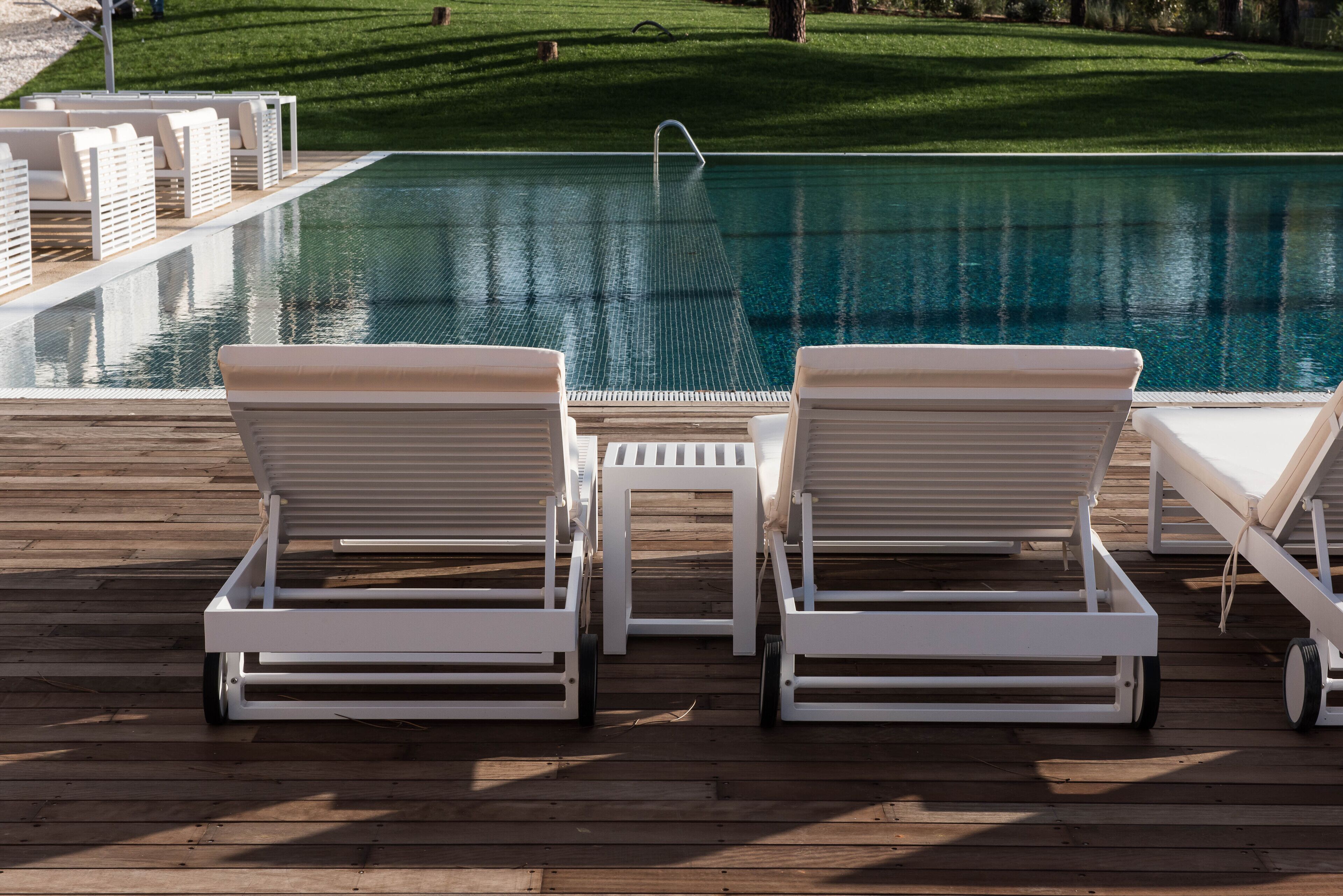 Zona de piscina con dos sillones de descanso y una mesita.