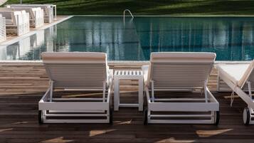 Zona de piscina con dos sillones de descanso y una mesita.