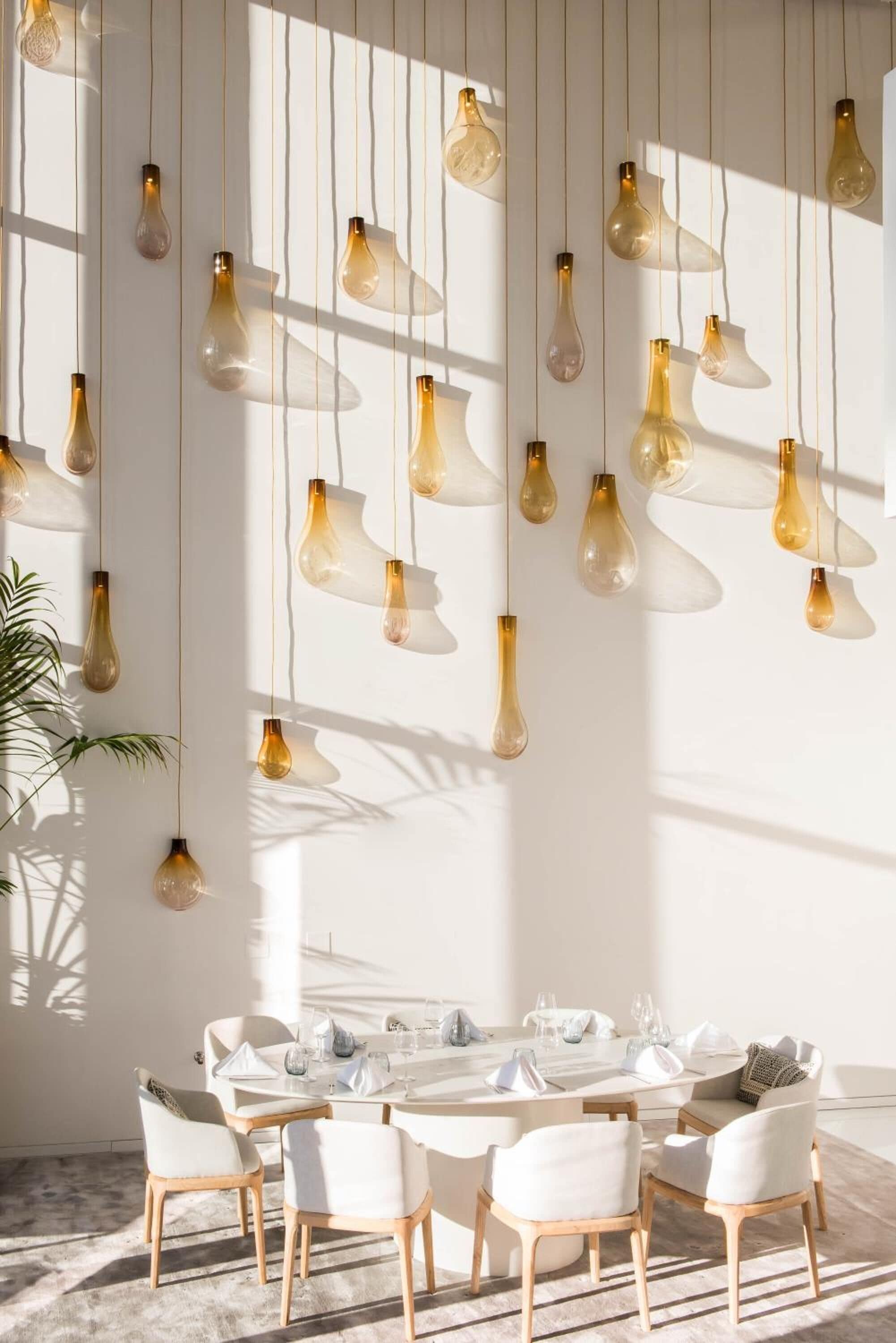 A dining area with a round table set for six, surrounded by white upholstered chairs.