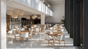 Een modern restaurant met een hoge plafond, hangende verlichting en een ruim, open design.