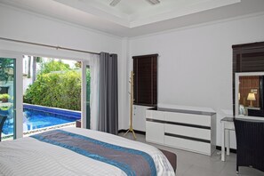 A bedroom with a bed, a desk, and a view of a swimming pool.