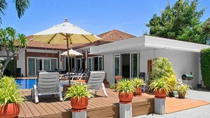 Ein modernes Haus mit Pool, Sitzgelegenheit im Freien und Topfpflanzen.