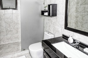 Un baño moderno con inodoro, lavamanos y ducha.