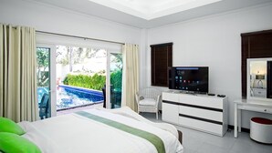 Ein Hotelzimmer mit Bett, Fernseher, Schreibtisch und Blick auf einen Außenpool.