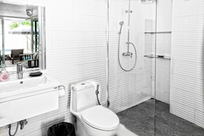 Un baño moderno con lavamanos blanco, inodoro y ducha con cerramiento de vidrio.