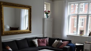 A living room with a black sofa, white coffee table, and a large mirror with a gold frame. - Best Stay Copenhagen-Henrik Steffens Vej (Frederiksberg)