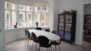 A room with a round table and chairs, a bookshelf, and a window with a view of buildings. - Best Stay Copenhagen-Henrik Steffens Vej (Frederiksberg)