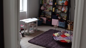 A room with a white table, a purple rug, a bookshelf, and a hanging chair. - Best Stay Copenhagen-Henrik Steffens Vej (Frederiksberg)