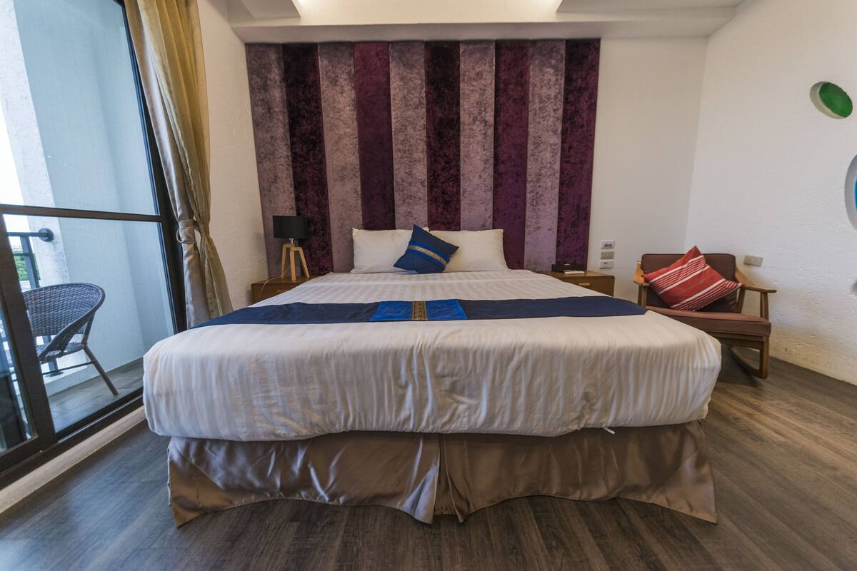 A hotel room with a large bed, a view of the balcony, and a modern design.